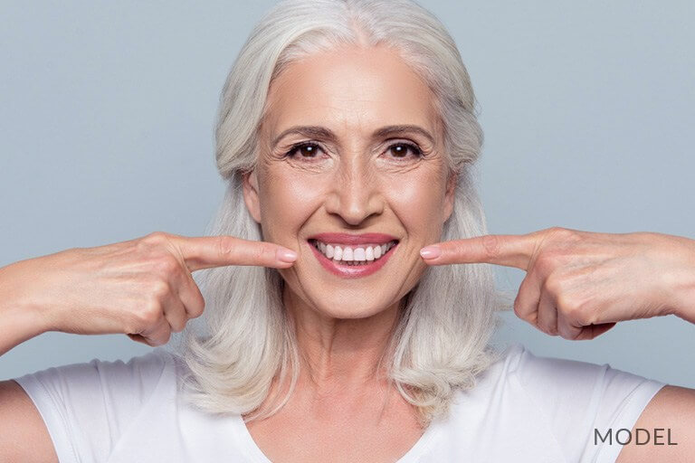 Mature Female Pointing At Teeth after dental implant procedure and sinus lift
