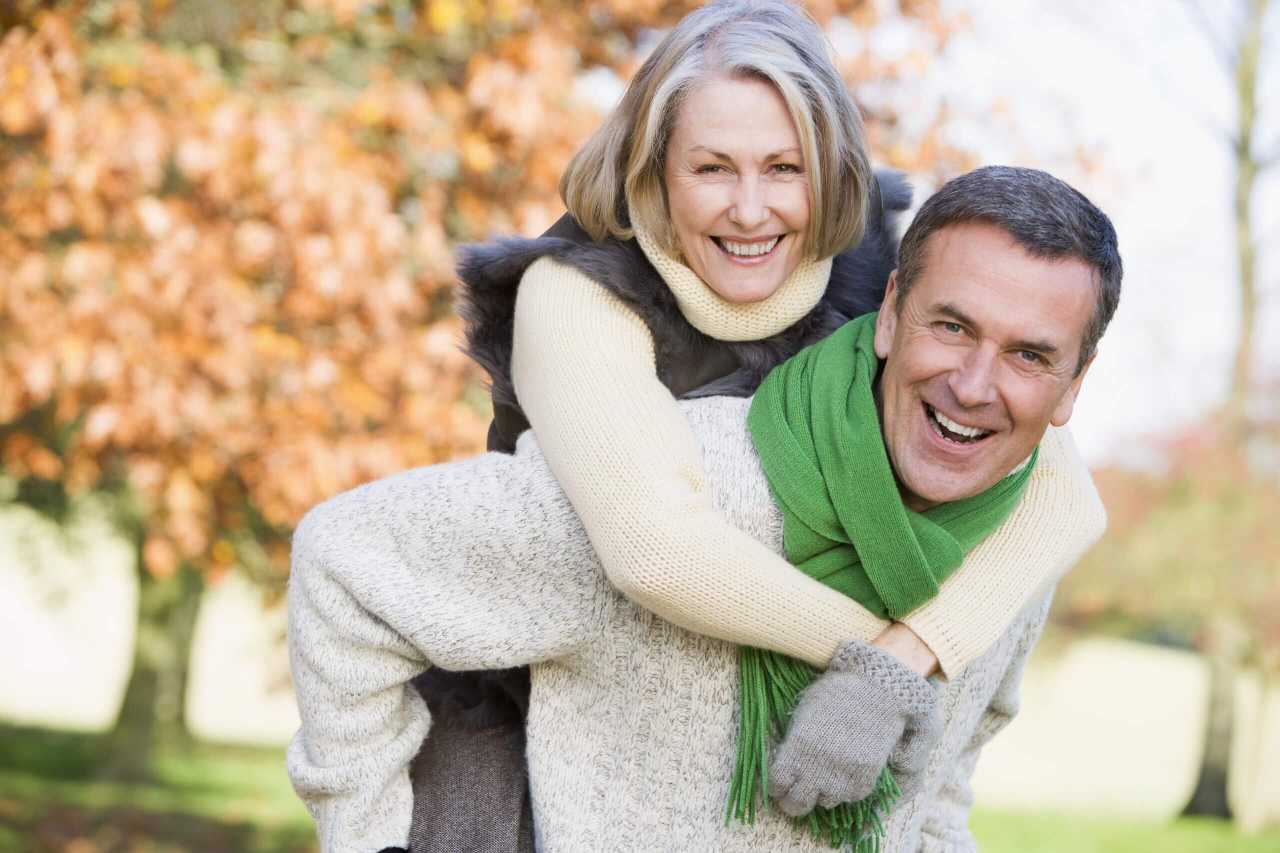 Mature Male Carrying Mature Female On Back Outdoors showing that dental implants are ideal at any age