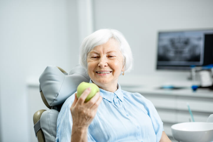 dental implants woman holding apple