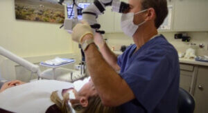 Dr. Kissel performing a dental microsurgery periodontal procedure while looking through a surgical microscope