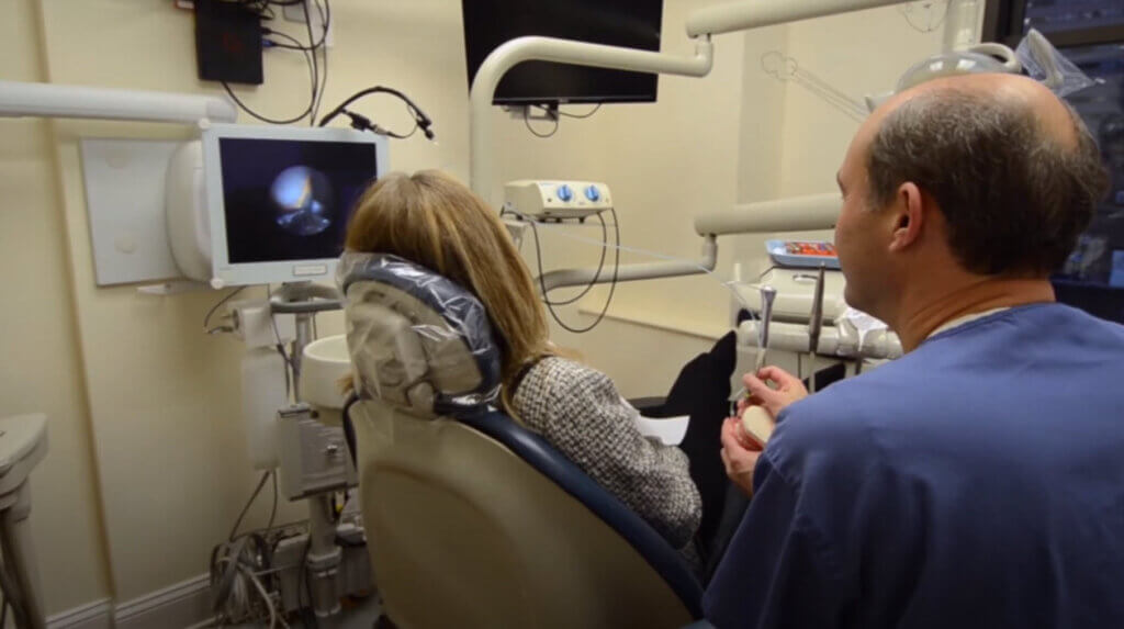 NYC periodontist, Dr. Kissel, with female patient using Perioscope to show her the treatment for Periodontitis
