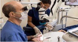 Dr Kissel using microscope to treat patient with dental microsurgery