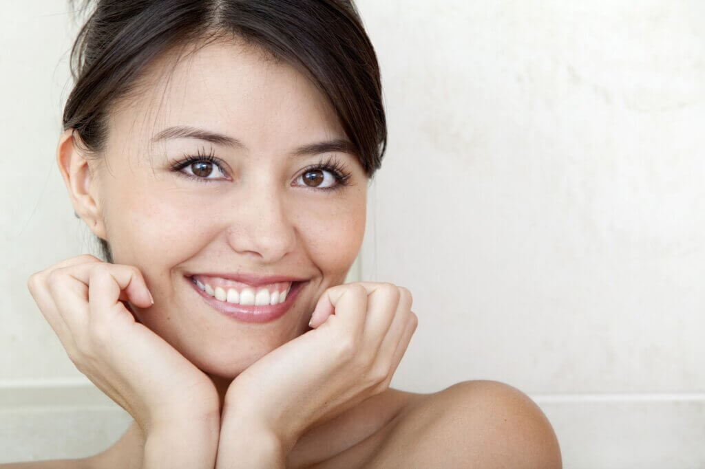 Smiling Brunette Female Resting Chin On Curled Hands