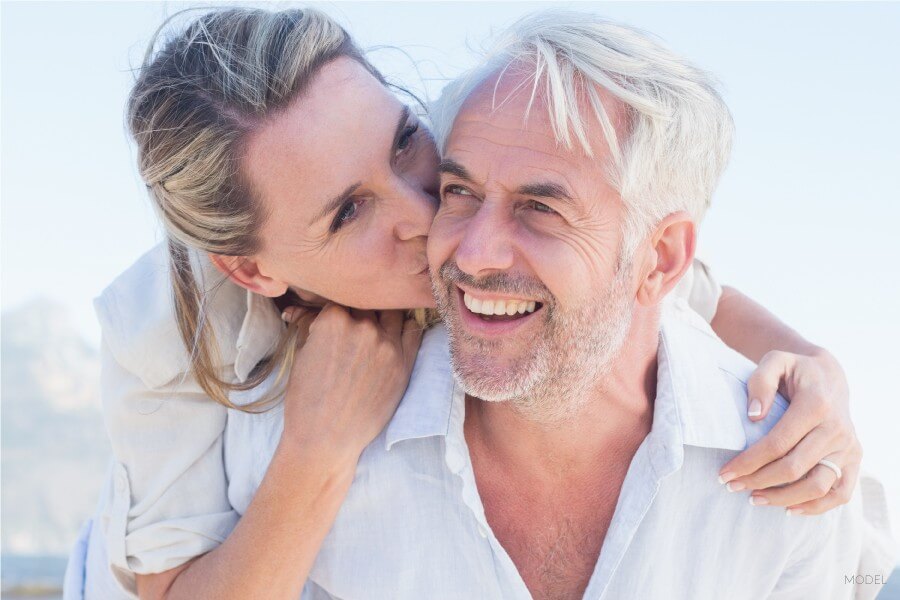 Elderly Female Embracing and Kissing Mature Male From Behind after dental implant microsurgery